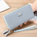 Detailed view of light blue leather long wallet, double zipper design and convenient wrist strap. - Blue