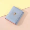 Close-up of the light blue tri-fold wallet detail featuring a cute bow and bear outline design. - Blue