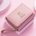 Pink short women's wallet detail showcasing triple-fold design and cute rabbit metal decor. - Pink