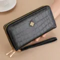 Black long double zipper wallet detail showing crocodile texture and elegant metal flower charm. - Black
