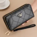 Black quilted long wallet detail with dual zippers, wrist strap and metal logo hardware. - Black