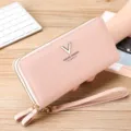 Pink long wallet detail view featuring pebbled PU leather, dual zippers and wrist strap. - Pink