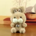 Détail en gros plan du pendentif lapin en peluche marron avec nœud brillant et collier cœur. - Style Coeur / Beige / Environ 15cm