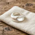 Close-up detail of irregular matte silver open ring on linen pouch, unique geometric design. - Frosted Matte Silver Streamline Style (JZ5601-1) / Open Adjustable