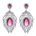 Primo piano dettagliato di lussuosi orecchini pendenti in zircone ovale rosa e cristalli. - Rosso rosa