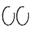 Close-up of oversized black and gold bamboo hoop earrings featuring detailed segmented design. - Black