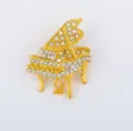 Detailed view of a gold-plated piano brooch encrusted with sparkling rhinestones for apparel. - KC Gold