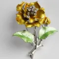 Close-up of elegant camellia flower brooch with sparkling rhinestones and green enamel leaves. - Silver Base Golden Yellow