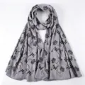 Detailed view of the elegant grey floral long scarf with black leaves and gold glitter accents. - Gray