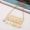 Close-up detail of gold metallic carved leaf tassel bib necklace fashion jewelry. - Gold