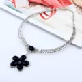 Nahaufnahme Detail der Vintage silberfarbenen Metall-Choker-Halskette mit schwarzem Blumenanhänger. - Antiksilber Schwarz