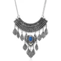 Close-up of vintage metal bib statement necklace with leaf engravings, blue stone and fringe. - Antique Silver + Blue