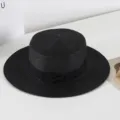 Detail view of a stylish black flat top straw hat with ribbon bow for summer beach travel. - M (56-58cm) / Black