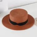 Close-up of a vintage flat-top straw hat featuring a chic black ribbon bow detail. - M (56-58cm) / Brown