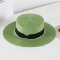 Green straw boater hat detail view, featuring a classic black ribbon bow on white background scene. - M (56-58cm) / Green