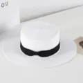 Details of the white straw flat-top hat with black bow ribbon, summer sun protection. - M (56-58cm) / White