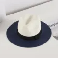 Detail view of a chic women's straw fedora hat with white crown, black bow band, and navy brim. - M (56-58cm) / Navy Blue