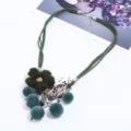 Collana statement in camoscio verde con fiore di lana, pon pon e ciondoli in metallo. - Verde