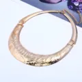 Nahaufnahme Detail der breiten goldenen Statement Metall Halsreif Kette mit geprägtem Muster. - Roségold