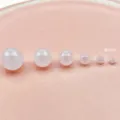 Primo piano dettagliato che mostra più perline rotonde in acrilico bianco latte traslucido. - 4mm / Bianco latte