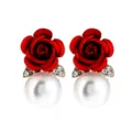 Nahaufnahme der eleganten roten Rosenblüte und weißen Perlenohrringe mit Strasssteinen. - Rot
