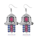 Nahaufnahme von vintage böhmischen Hamsa-Hand Ohrringen mit bunten Steinen und Perlen. - Fuchsia