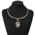 Close-up of the gold-tone metal choker featuring a hollow geometric eye pendant with clear stone. - Marquise Style