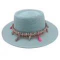 Detailansicht eines mintgrünen flachen Strohhutes mit Ethnoband und pinken Quasten. - M (56-58cm) / Grasgrün