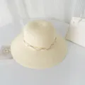 Gros plan détaillé de l'élégant chapeau de paille beige avec perles et ruban de dentelle. - M (56-58cm) / Crème