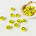 Primo piano dettagliato di perline acriliche gialle con faccine sorridenti in una conchiglia. - Grande Confezione da 10 Pezzi (9mm) / Faccina Sorridente Gialla