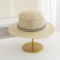 Gedetailleerd overzicht van beige strohoed met elegante parel gevlochten band, zomers. - M (56-58cm) / Beige