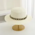 Vista detallada de un elegante sombrero de paja de copa plana con cinta tejida metálica. - M (56-58cm) / Crema