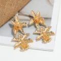 Elegante vergoldete Metallblumen Ohrringe Detailansicht, stilvoller langer Modeschmuck Trend. - Gold