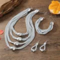 Detaillierte Nahaufnahme des silbernen mehrsträngigen Mesh-Kettenschmucksets mit modischen Metallperlen. - Weiß