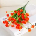 Gros plan détaillé d'un bouquet de fleurs artificielles orange sur un livre décoratif. - Orange