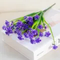 Gros plan d'un bouquet de fleurs violettes artificielles sur livre déco blanc pour la maison. - Violet