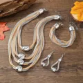 Nahaufnahme des mehrlagigen Ketten Modeschmuck Sets mit Halskette, Armband und Ohrringen. - Gold und Silber