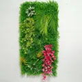 Détail du mur de plantes artificielles avec des feuilles vertes et des fleurs colorées. - WBD1