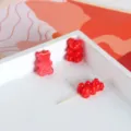 Primo piano di perline in acrilico a forma di orsetto rosso in vassoio bianco per gioielli. - Stile 04 Orso Rosso / Rosso