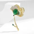 Elegant gold-plated ginkgo flower brooch with emerald green teardrop crystal and pave zirconia. - Gold