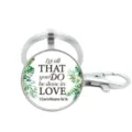 Detail view of metal keychain with inspirational quote glass pendant and green leaves design. - Style 4