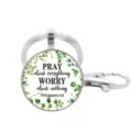Gedetailleerd overzicht van een metalen sleutelhanger met religieuze quote en groene bladeren. - Stijl 9