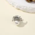 Close-up of delicate spider insect brooch with pearl and sparkling rhinestones for elegant outfits. - Spider