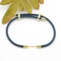 Dark blue braided leather bracelet with gold metal hardware, adjustable clasp accessory for daily wear. - Dark Blue