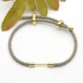 Grey braided leather cord bracelet with golden metal slider beads and DIY fashion accessory. - Gray
