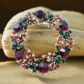 Close-up detail of vintage Christmas wreath brooch with red green rhinestones and gold tone. - 5cm (18.8g) / Red