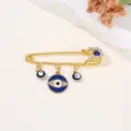 Gros plan détail de la broche épingle de sûreté œil grec doré avec des strass étincoyants et bleus. - 5.8x4.5x0.9cm / Bleu