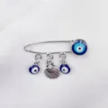 Detailopname van boze oog broche met schelp hanger, zilverkleurig metaal uniseks mode. - Schelp Stijl (3)