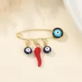 Gros plan d'une broche épingle dorée avec perles œil turc et pendentif piment rouge pour col. - Style Piment / 3.8x2.8cm