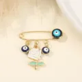 Gold-tone safety pin brooch featuring evil eye charms and a white rose pendant accessory. - White Rose and Evil Eye Style
